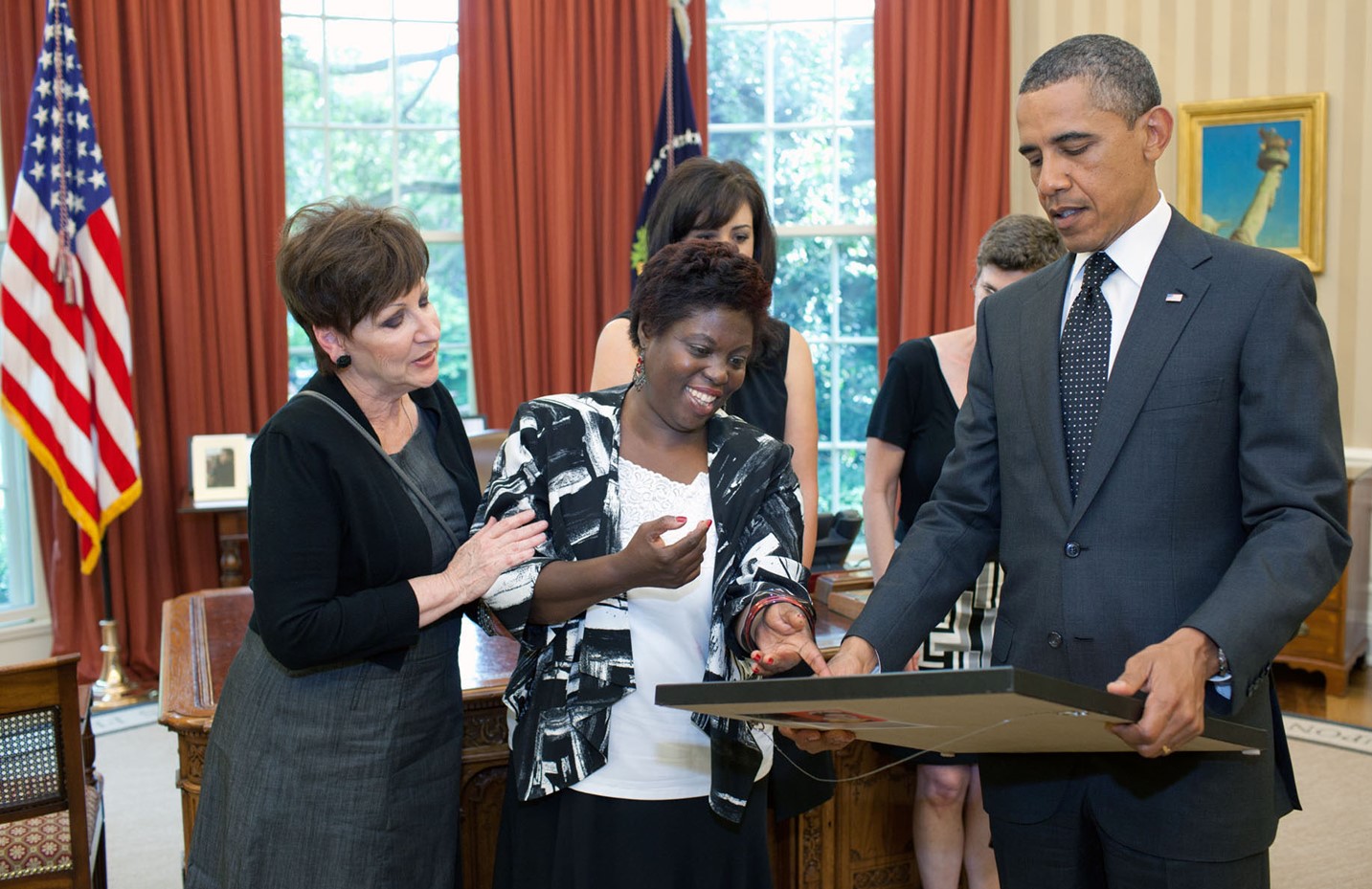 Lois Curtis, plaintiff in Olmstead v. L.C., (center) presents President Barack Obama with a self-portrait of herself as a child that she painted. The Oval Office, 20 June 2011